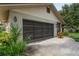Attached garage with a decorative door and landscaping at 8700 Wind Mill Dr, New Port Richey, FL 34655