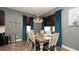 Dining room with wood table, white chairs, elegant chandelier, and teal curtains at 905 Old Windsor Way, Spring Hill, FL 34609