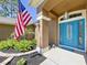 Inviting entryway with a blue door, decorative sidelights, and lush landscaping at 9152 Bunting Rd, Weeki Wachee, FL 34613