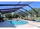 Enclosed pool in lanai with outdoor furniture and grilling area surrounded by a wooded landscape at 9152 Bunting Rd, Weeki Wachee, FL 34613