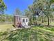 Outdoor shed with double doors, surrounded by a grassy lawn and mature trees at 9152 Bunting Rd, Weeki Wachee, FL 34613