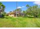 Beautiful backyard featuring lush green lawn, mature trees, and a screened-in lanai perfect for outdoor living at 9161 Southern Comfort Ct, Weeki Wachee, FL 34613