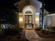 Inviting home entrance featuring double doors, arched entryway, and elegant landscaping at night at 9161 Southern Comfort Ct, Weeki Wachee, FL 34613
