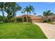 Charming home with meticulously maintained lawn, mature palm trees, and tile roof, creating a welcoming entrance at 9161 Southern Comfort Ct, Weeki Wachee, FL 34613