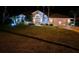 Night view of beautiful one-story home with manicured front lawn, palm trees, and elegant lighting at 9161 Southern Comfort Ct, Weeki Wachee, FL 34613