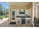 A fully functional outdoor kitchen features a grill, mini-fridge, and bar with a pass-through window to the interior at 9161 Southern Comfort Ct, Weeki Wachee, FL 34613