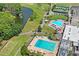 Scenic aerial view featuring a resort-style swimming pool, tennis courts, lush landscaping, and a serene pond at 9622 Brassie Ct # 9, New Port Richey, FL 34655