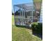 Screened patio has chairs and a table, surrounded by lush green lawn and garden at 9622 Brassie Ct # 9, New Port Richey, FL 34655