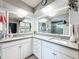 Bright bathroom with dual sinks, white cabinets, grey countertop, and large mirrors at 10411 Ireland St, Spring Hill, FL 34608