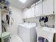 Well lit laundry room with updated appliances, tile floor and overhead storage at 10411 Ireland St, Spring Hill, FL 34608