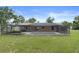 A backyard with a screened-in pool, complemented by green grass and trees at 10441 Mayflower Rd, Spring Hill, FL 34608