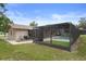 The backyard featuring the screened-in pool and a well-maintained lawn at 10441 Mayflower Rd, Spring Hill, FL 34608