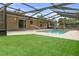 Backyard showcasing a screened-in pool, green lawn, and a home's exterior at 10441 Mayflower Rd, Spring Hill, FL 34608