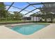 A refreshing swimming pool enclosed by a screened lanai with lush greenery at 10441 Mayflower Rd, Spring Hill, FL 34608