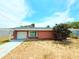 Charming single-story red brick home featuring an attached garage and a well-maintained lawn at 11034 Harding Dr, Port Richey, FL 34668