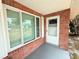 Inviting front porch with large windows, red brick and a white trimmed storm door at 11034 Harding Dr, Port Richey, FL 34668
