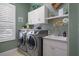 Well-equipped laundry room with modern washer and dryer, white cabinets, and ample counter space at 12403 Moneta Rd, Weeki Wachee, FL 34614