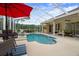Inviting screened-in pool area with a spa, bar, and dining area, surrounded by lush landscaping at 12403 Moneta Rd, Weeki Wachee, FL 34614
