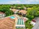 Aerial view showcases the pool, shuffleboard courts, and parking, complemented by mature trees and landscaping at 12920 Wedgewood Way # B, Hudson, FL 34667