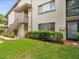 A charming building features a staircase to a unit entrance and lush green landscaping at 12920 Wedgewood Way # B, Hudson, FL 34667