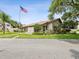 Community clubhouse featuring well-manicured lawns, mature trees, and an American flag for a welcoming ambiance at 12920 Wedgewood Way # B, Hudson, FL 34667
