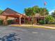 Community building exterior features covered entrance, ample parking, mature trees, and manicured landscaping at 12920 Wedgewood Way # B, Hudson, FL 34667