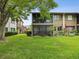 A condo with a large screened-in patio, surrounded by a lush green lawn and mature landscaping at 12920 Wedgewood Way # B, Hudson, FL 34667