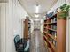 Hallway featuring bookshelves lining one wall and a view of an exit at the end of the hall at 12920 Wedgewood Way # B, Hudson, FL 34667