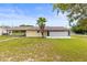 Back of the home featuring a screened in patio area and a well manicured lawn with a palm tree at 12936 Parkwood St, Hudson, FL 34669