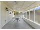 Covered back porch with screen enclosure, concrete flooring, and a quaint round table with glass top at 12936 Parkwood St, Hudson, FL 34669