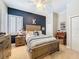 Cozy bedroom with blue accent wall, wooden furniture, plantation shutters, and a ceiling fan for added comfort at 13248 Linzia Ln, Spring Hill, FL 34609
