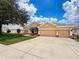 Beautiful tan single-story home with a three-car garage on a well-maintained lawn under a sunny sky at 13248 Linzia Ln, Spring Hill, FL 34609