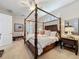 Bright main bedroom featuring a dark wood four poster bed, decorative furniture, and plantation shutters at 13248 Linzia Ln, Spring Hill, FL 34609