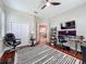 Bright home office with a striped rug, ceiling fan, and modern desk setup at 13248 Linzia Ln, Spring Hill, FL 34609