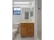 Bathroom features a light wood vanity, toilet, shower, mirror, and a window at 13307 Woodward Dr, Hudson, FL 34667