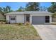 Charming single-story home featuring a well-maintained lawn, inviting facade, and a gray two-car garage at 13307 Woodward Dr, Hudson, FL 34667