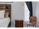This part of the main bedroom highlights a small bedside table with drawers, next to a window with a chair and bedside lamp at 14031 Hexam Rd, Brooksville, FL 34613