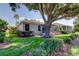 View of the side and rear of the home with a large tree and screened lanai at 14466 Tamarind Loop, Spring Hill, FL 34609