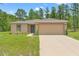 Inviting single-story home with a well-kept lawn, two-car garage, and lush greenery in the landscape at 15414 Green Jay Rd, Weeki Wachee, FL 34614