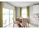 Cozy dining area with a round wooden table, comfortable chairs, green drapes, and sliding glass doors at 1699 W Palms Dr, Port Charlotte, FL 33953
