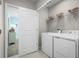 Well-lit laundry room with white washer and dryer, wire shelving, and access to another room at 1699 W Palms Dr, Port Charlotte, FL 33953