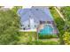 Aerial view of a screened-in pool, blue roof, and green backyard surrounded by well-maintained landscaping and a fence at 18902 Saint Laurent Dr, Lutz, FL 33558
