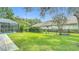 Serene backyard featuring lush green lawn, black fence, mature trees, and screened pool area at 18902 Saint Laurent Dr, Lutz, FL 33558