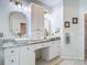 Stylish bathroom with double vanity, white cabinets, granite countertops, decorative mirrors and lighting at 18902 Saint Laurent Dr, Lutz, FL 33558