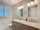 Bathroom featuring a double vanity with marble countertops, framed mirrors, and shuttered window at 18902 Saint Laurent Dr, Lutz, FL 33558