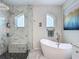 Modern bathroom featuring a glass-enclosed shower, soaking tub, and arched windows for natural light at 18902 Saint Laurent Dr, Lutz, FL 33558