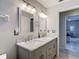 Neutral bathroom features a double vanity, framed mirrors, and a door to the backyard at 18902 Saint Laurent Dr, Lutz, FL 33558