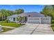 Charming single-story home with manicured lawn, palm trees, and a three-car garage at 18902 Saint Laurent Dr, Lutz, FL 33558