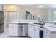 Bright kitchen featuring quartz countertops, stainless steel dishwasher, and white cabinets with stainless steel hardware at 18902 Saint Laurent Dr, Lutz, FL 33558