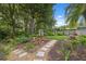 Tranquil backyard features a manicured lawn, garden with a stone pathway, mature trees, and lush landscaping at 19418 Morden Blush Dr, Lutz, FL 33558